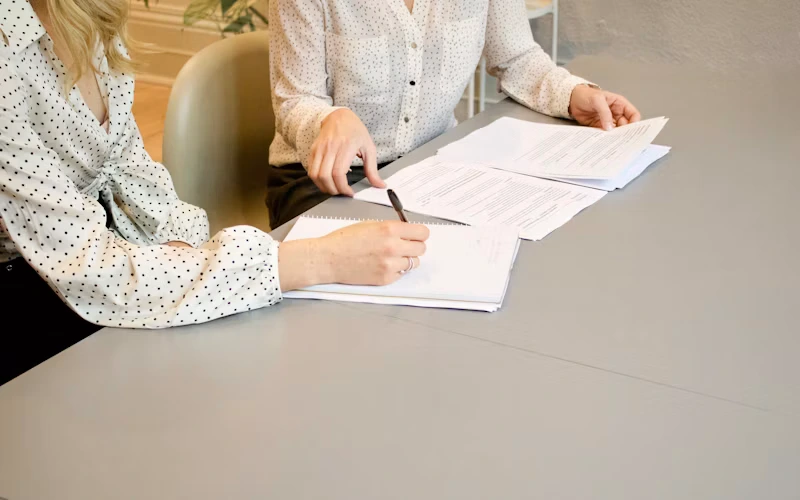 Close-up of hands writing on paper with a pen at a desk